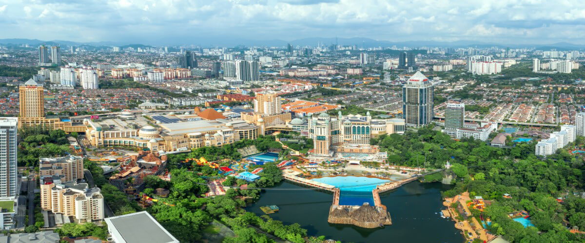 An aerial view of Sunway City Kuala Lumpur, with Sunway Lagoon and the Sunway Lagoon lake in view alongside Sunway Resort and Sunway Pyramid, amidst sprawling greenery and trees