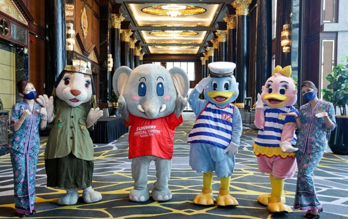 A full landscape shot featuring Sunway City Kuala Lumpur mascots – Leona representing Sunway Pyramid, Elfie representing Sunway Healthcare Group, and Captain Quack as well as Lady Quack representing Sunway Lagoon Theme Park, poised in between two Malaysia Airlines stewardesses in the lobby of Sunway Resort Hotel’s Grand Ballroom.