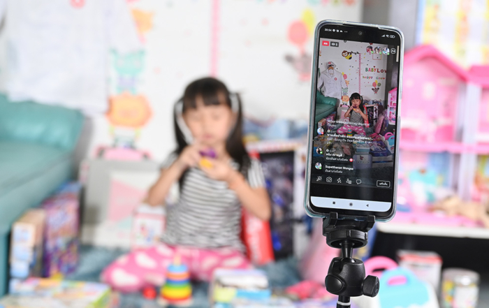 A shot of a phone with a TikTok livestream of a little girl, who is playing with her pink toys.