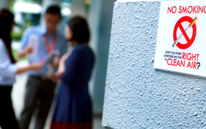 A No Smoking Sign on a grey wall at Sunway Leadership Centre in Menara Sunway, with three staff in the background.