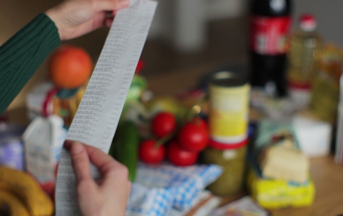 mid-shot of a woman holding a receipt, with groceries in the background