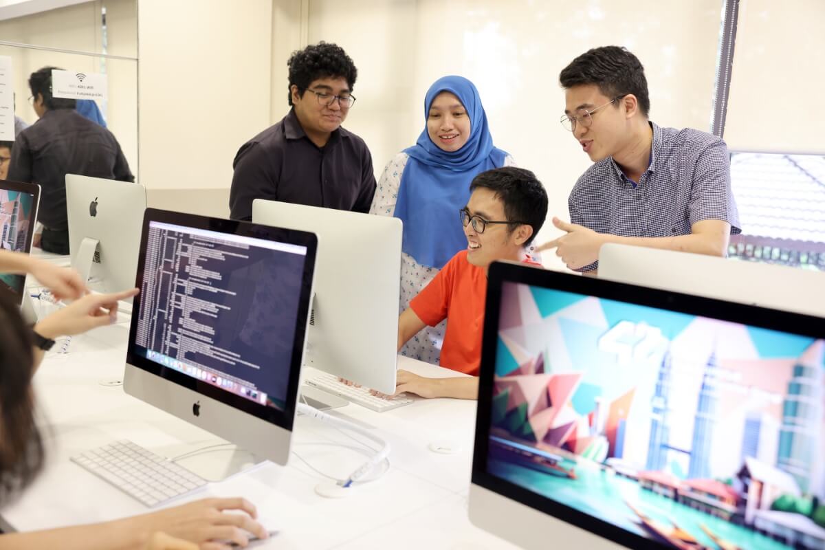 A multiracial group of students looking at a computer at 42KL. They are discussing coding.