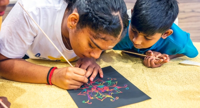 Close-up shot of two children drawing a colourful kolam