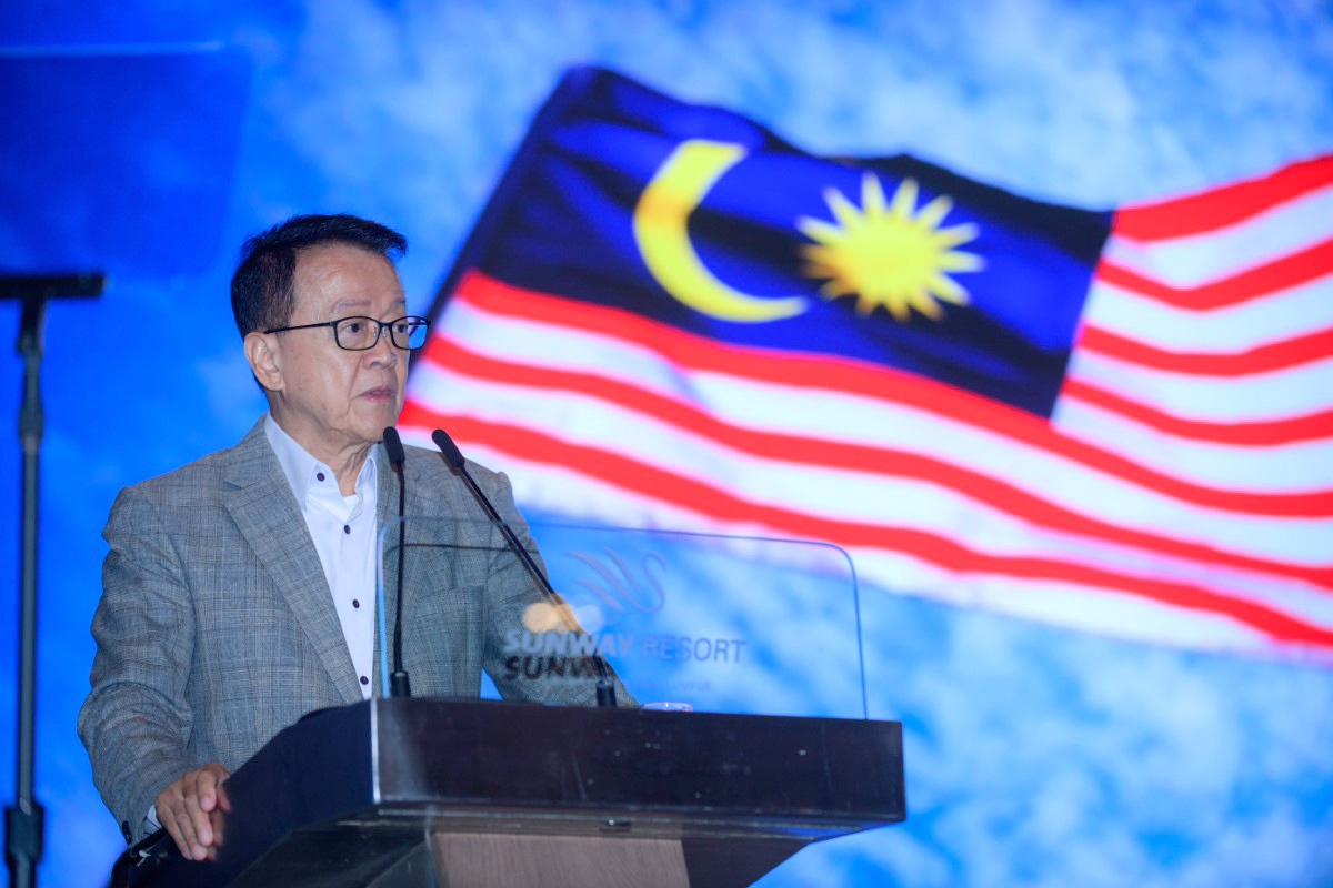 Tan Sri Sir Dr. Jeffrey Cheah making a speech with the Malaysian flag flying in the background.