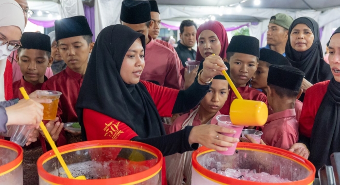 A mid-shot of Sunway staff at Sinar Ramadan helping to pour sirap bandung for the children.