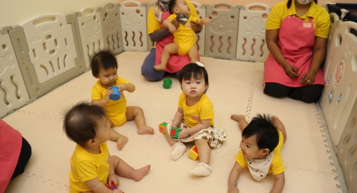 A far shot of babies at Sunway Little Sunshine Childcare Centre, along with two staff at the background.