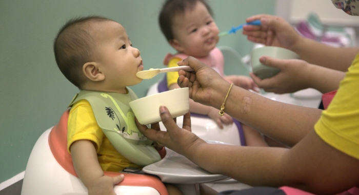 A close-up shot of a staff at Sunway Little Sunshine Childcare Centre feeding a baby