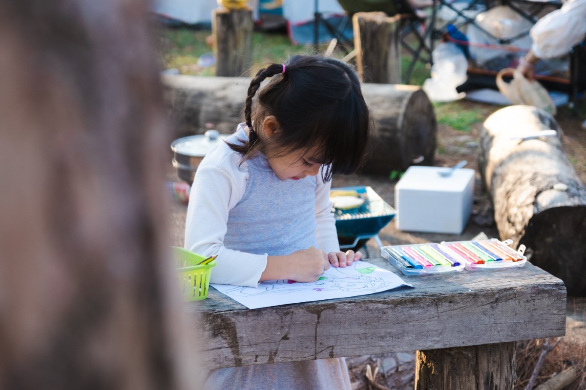 A young girl doing some studying outdoors in disadvantageous settings.