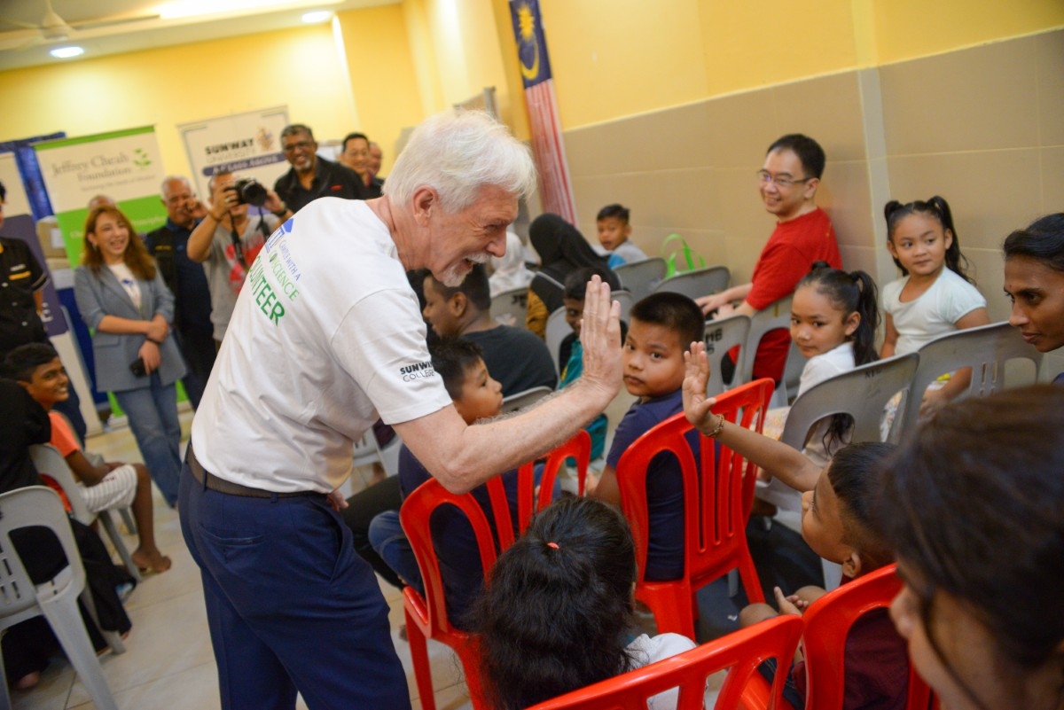 Medium shot of President of Sunway University Prof. Sibrandes high fiving a child at Desa Mentari.